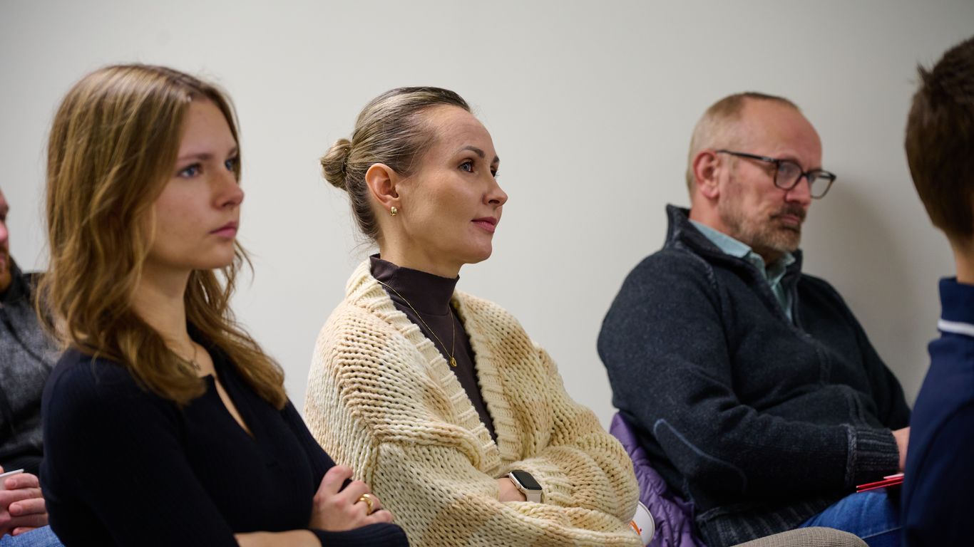 People sitting in a room, attentively listening to a presentation.