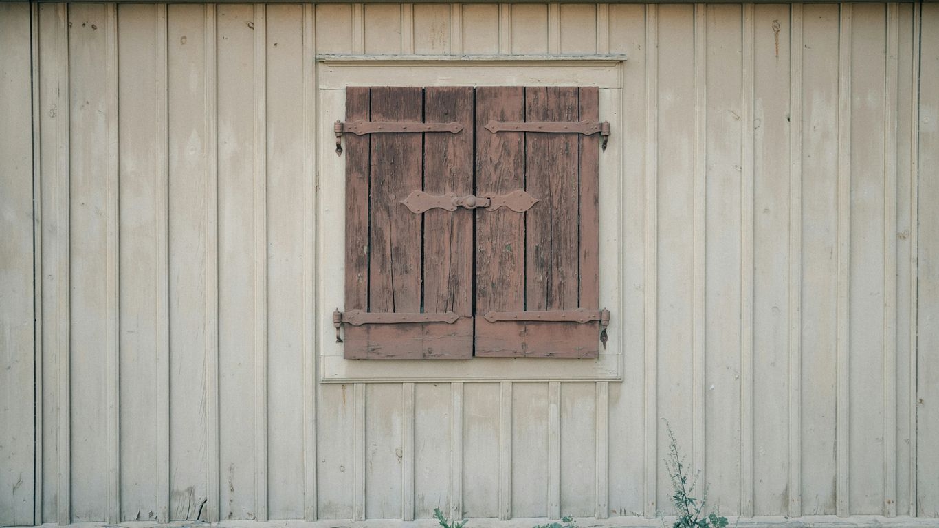 Weathered wooden shutters on a light-colored building.