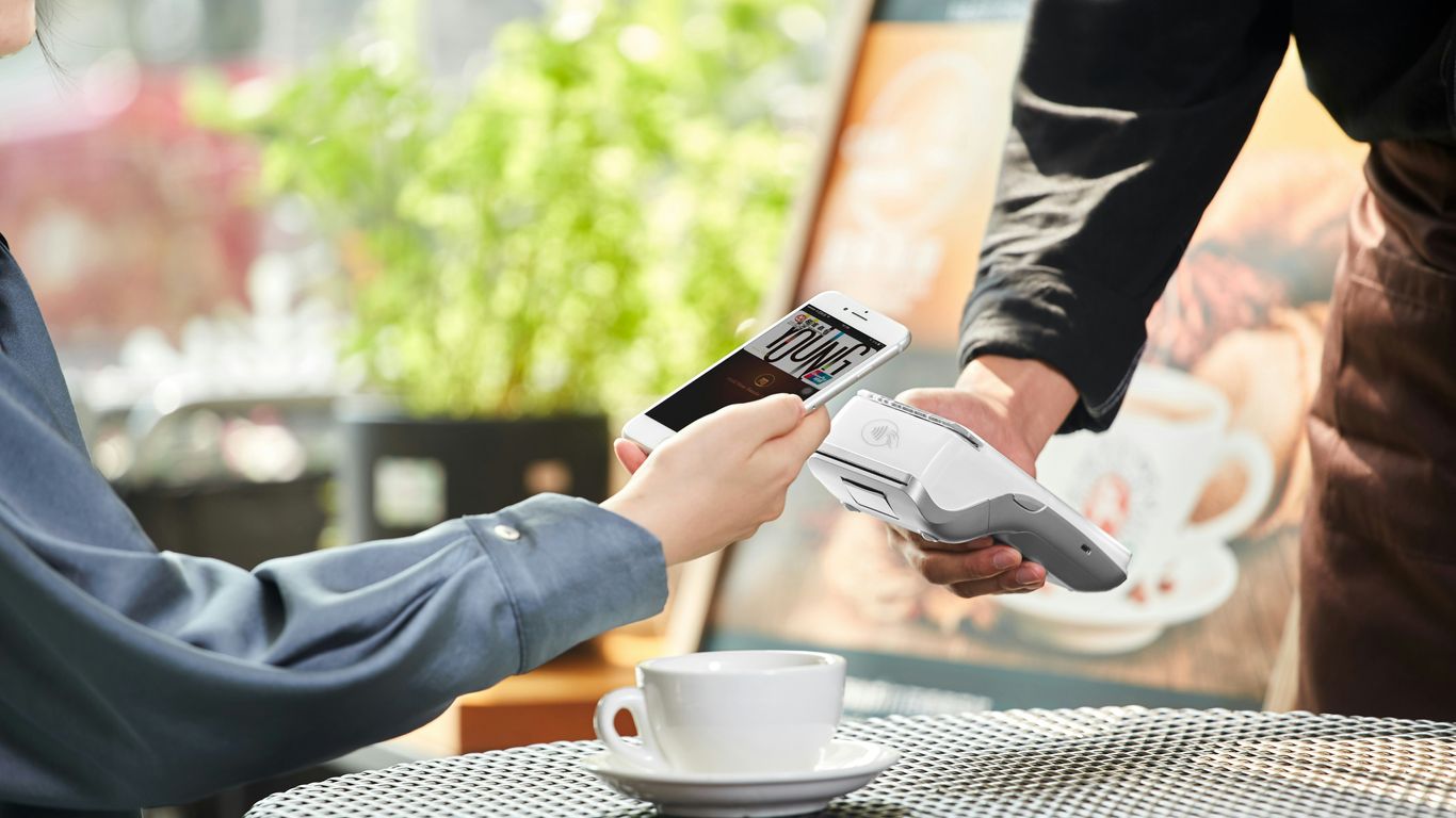 person holding white ceramic mug and black smartphone