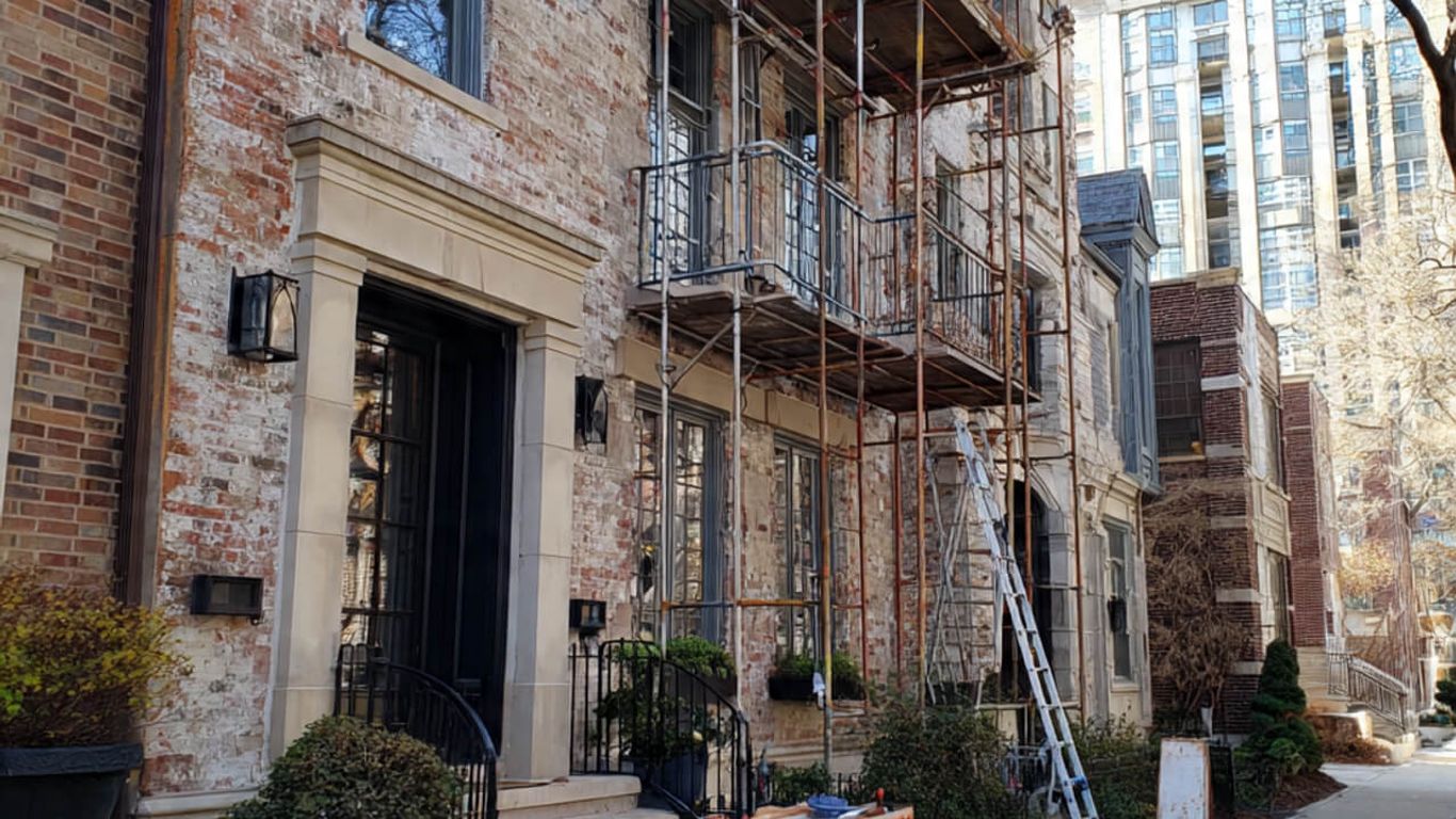 Building under renovation with scaffolding and construction materials on sidewalk.