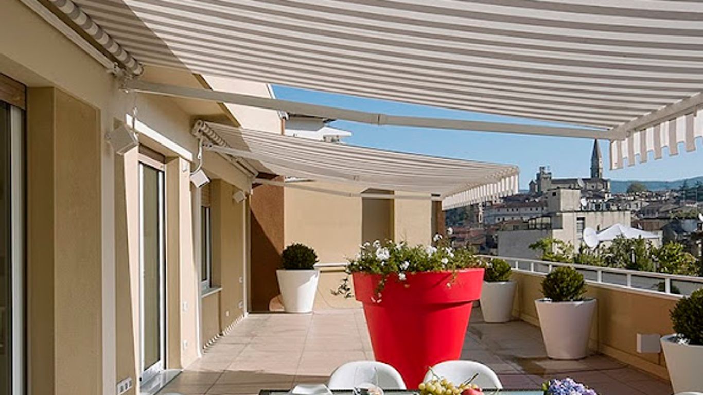 A sunny terrace with striped awnings, dining table, and city view.