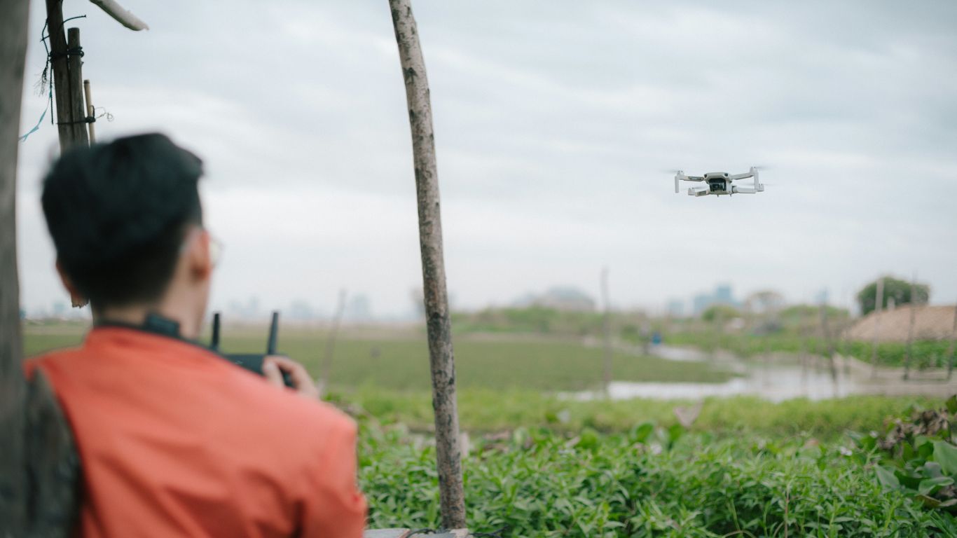 man in orange shirt standing near green grass field during daytime