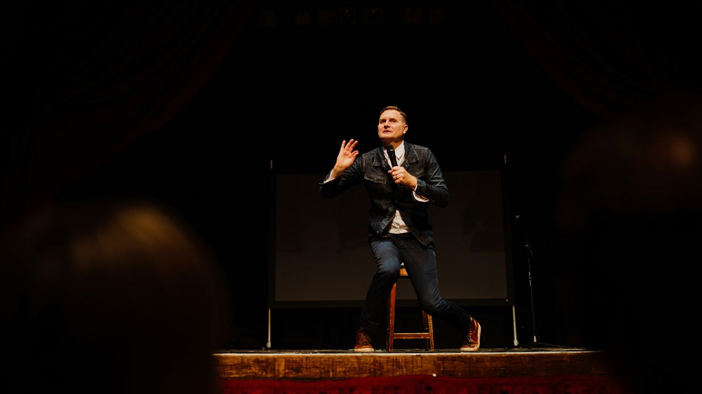 man in black suit singing on stage