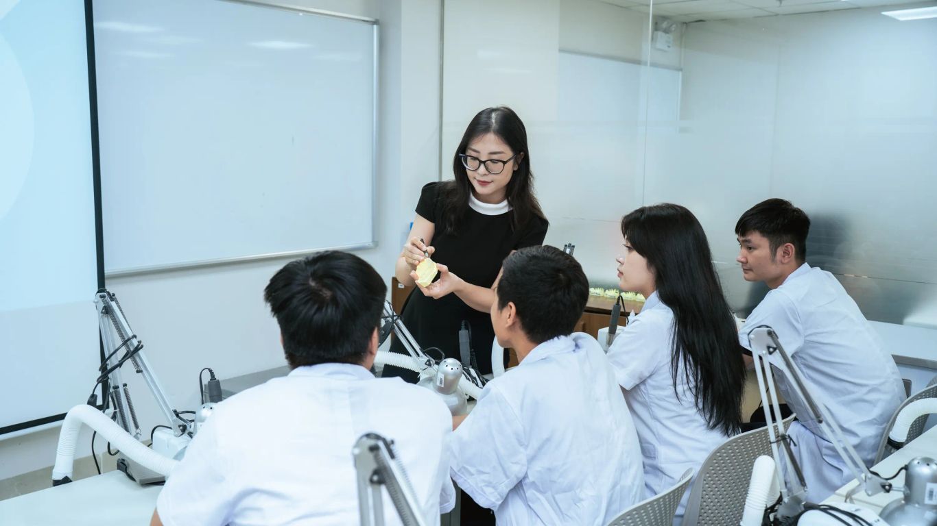 A person demonstrates a dental model to students in a lab.