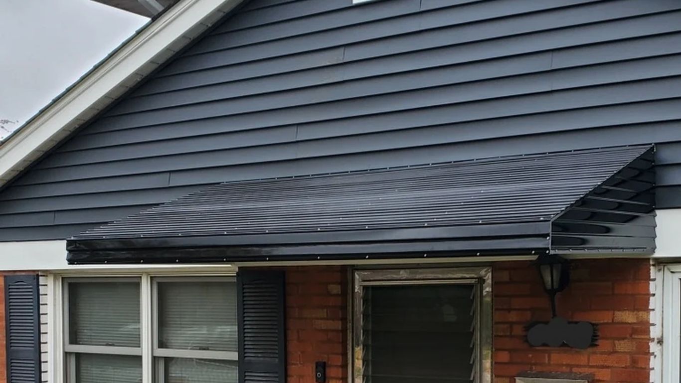 A black awning covers the entrance of a brick house.