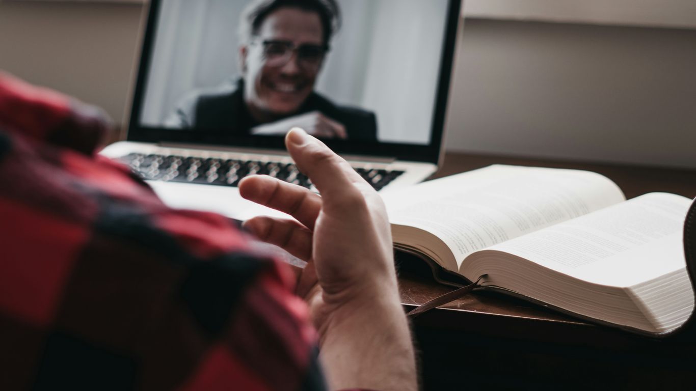 person in red and black plaid long sleeve shirt using black laptop computer