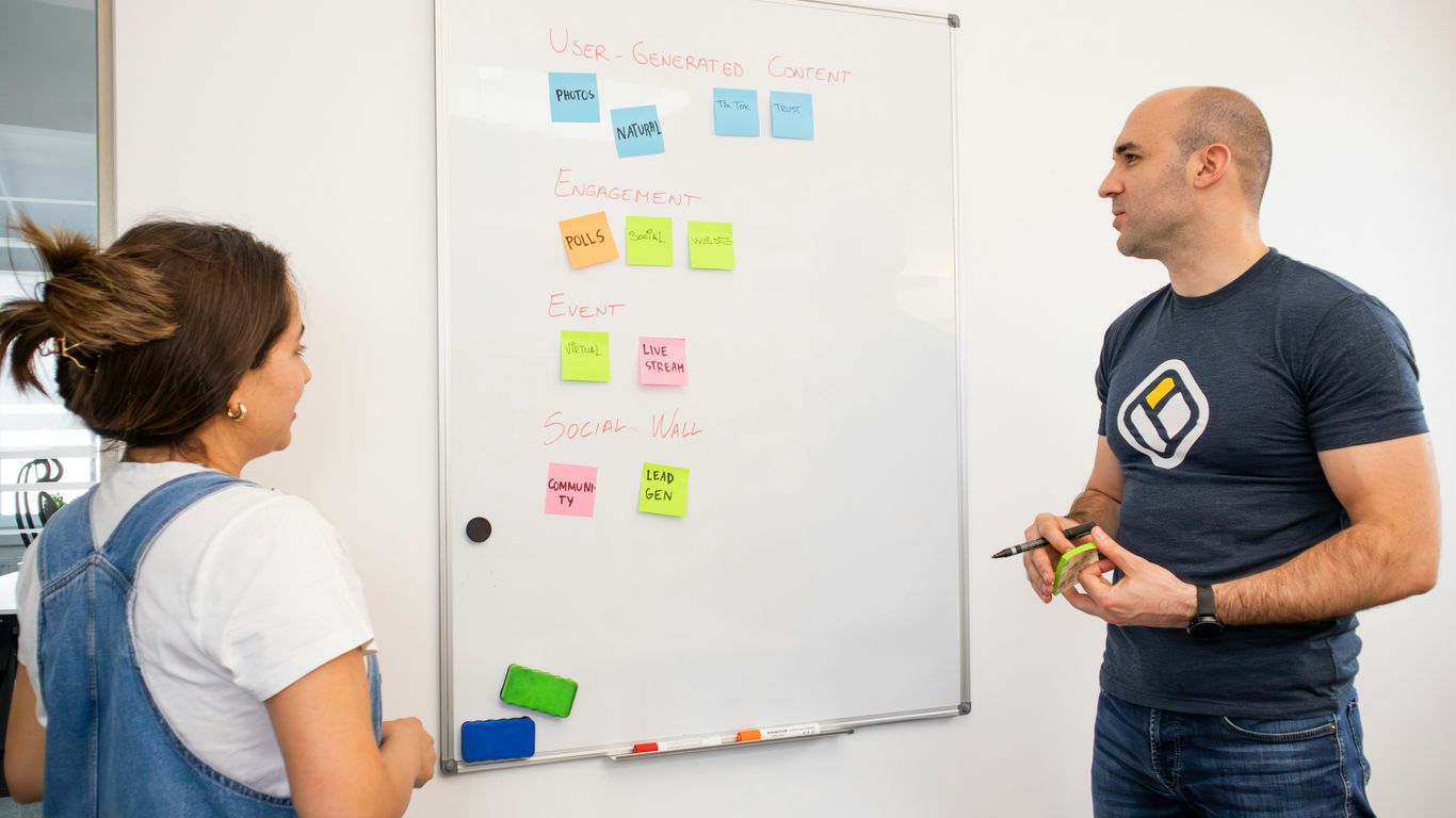 a man and a woman standing in front of a white board