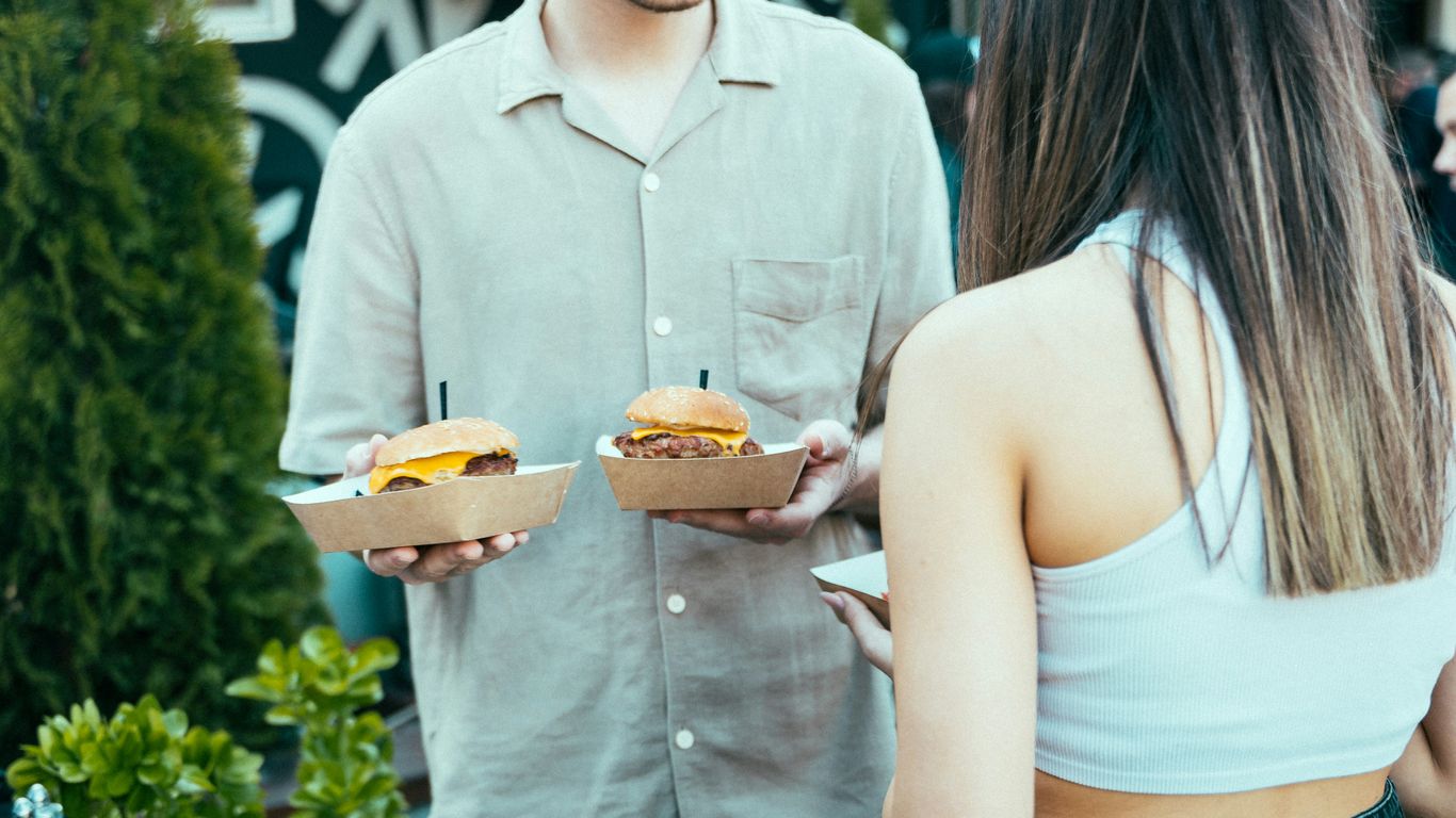 a man and a woman holding sandwiches in their hands