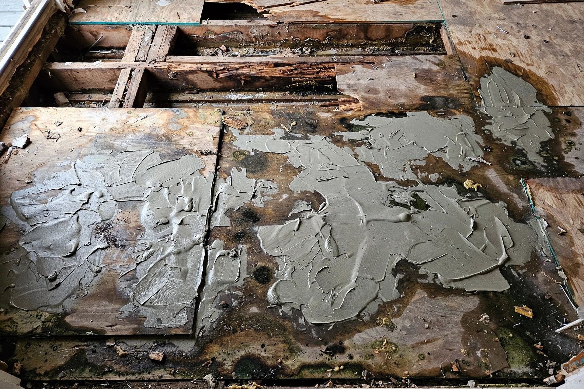 A poorly prepared subfloor with uneven patches, exposed timber and signs of moisture before new flooring is installed