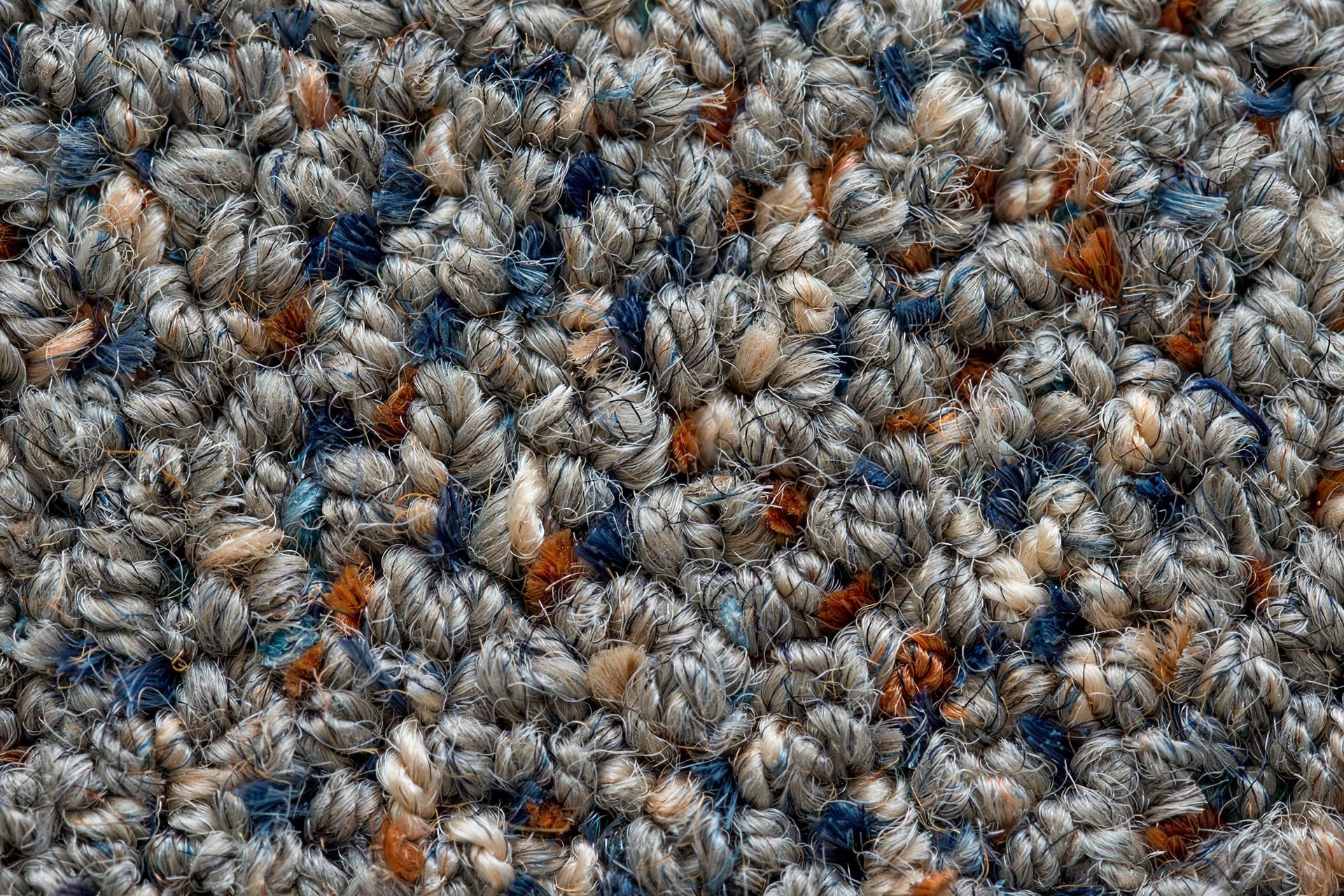 Close-up of flecked heathered carpet fibres in a mid-tone, showing contrasting yarn colours and a dense textured pile