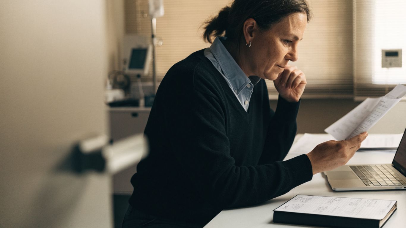 Practice manager viewing a laptop beside clinic scheduling notes