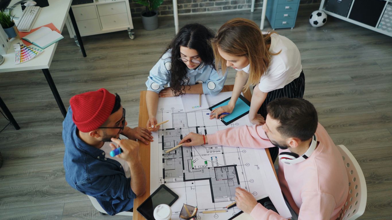 a group of people sitting around a table working on a project