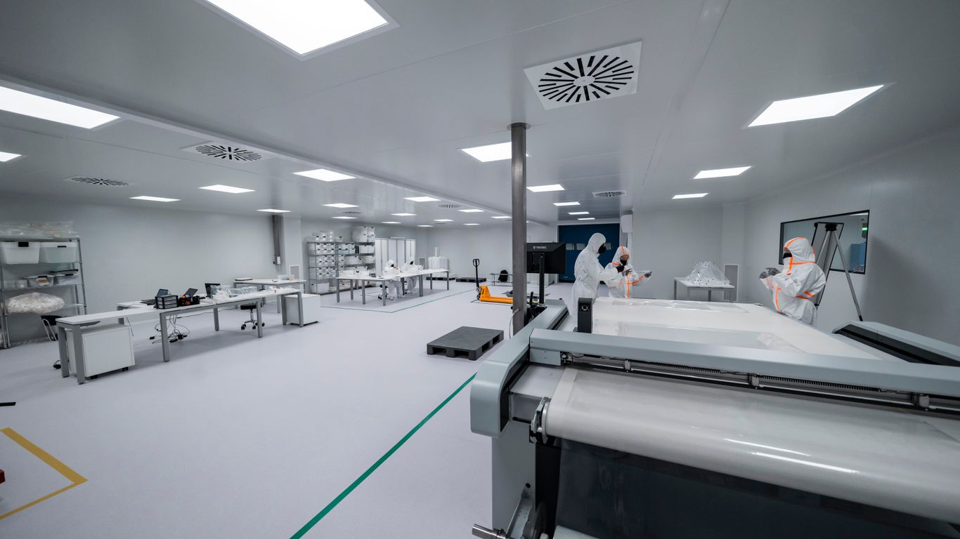 Workers are inside a clean room manufacturing something.