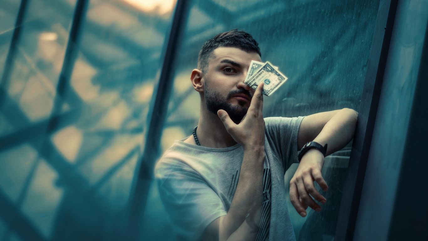 a man leaning against a glass wall talking on a cell phone
