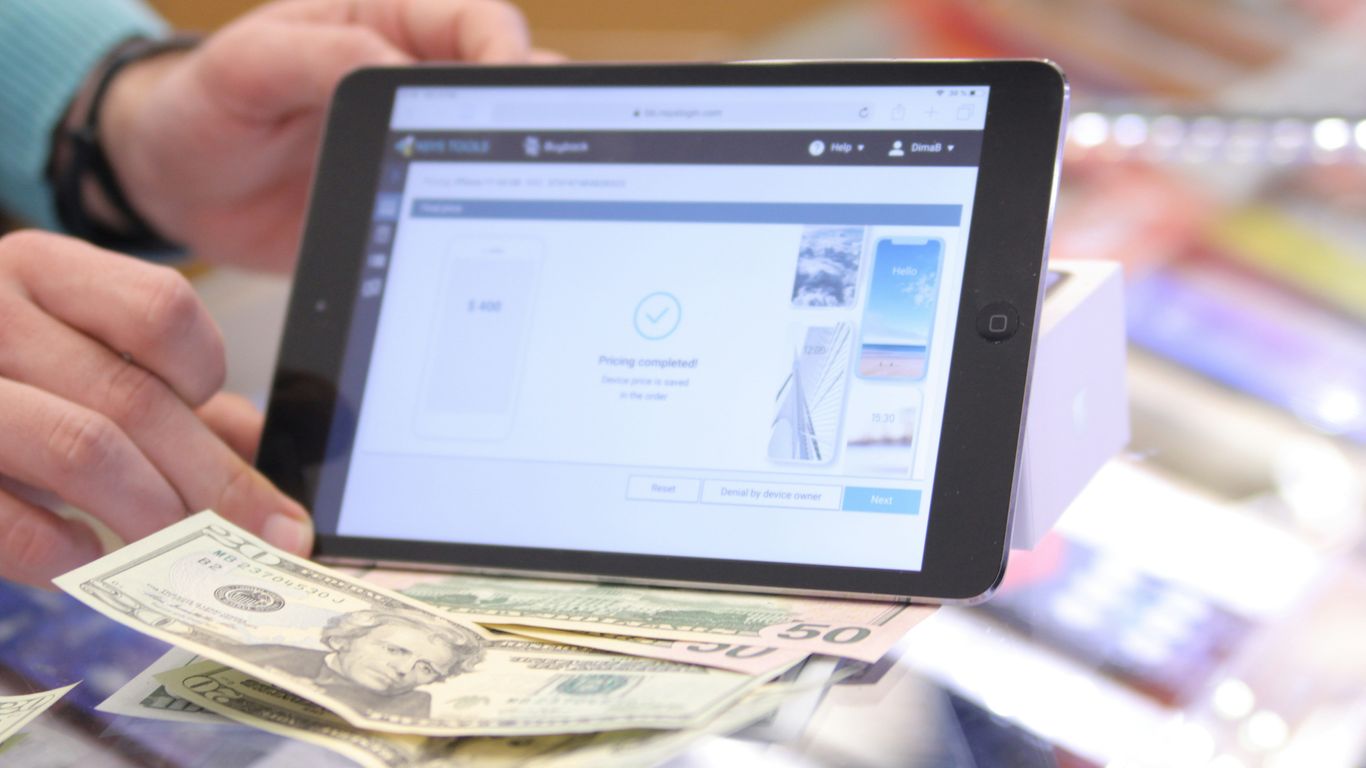 a person holding a tablet over a pile of money