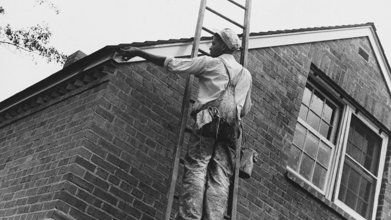 Man painting the side of a brick house