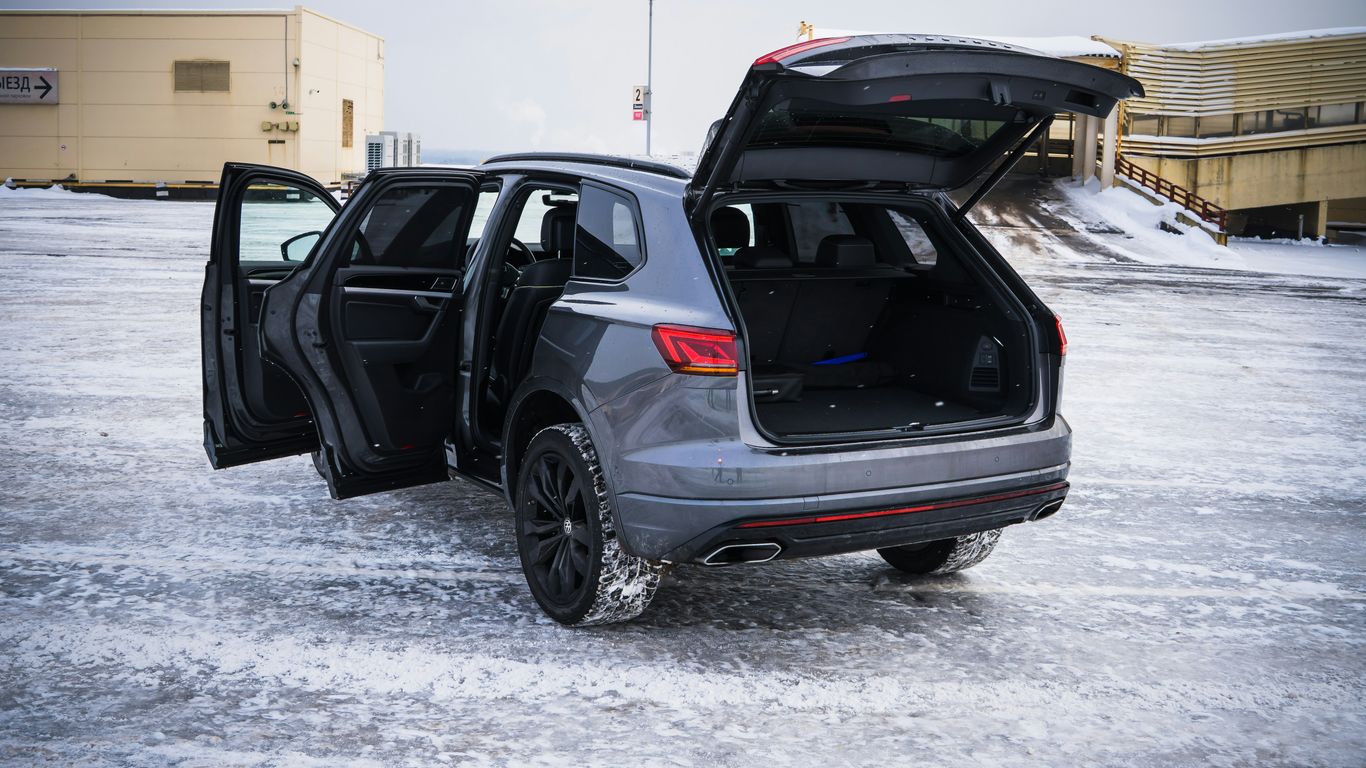 Gray suv with open doors and trunk in snow.