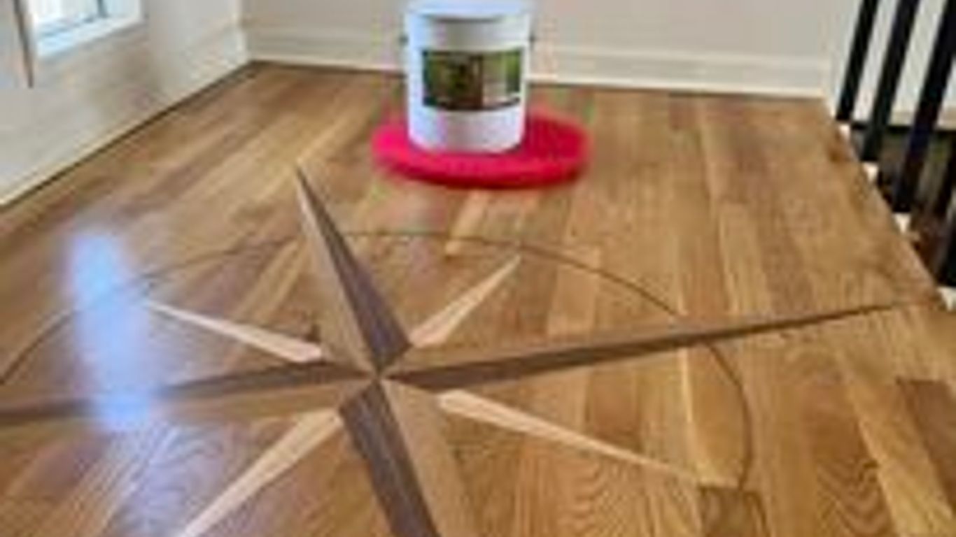 Wooden floor with a decorative compass design and paint can.