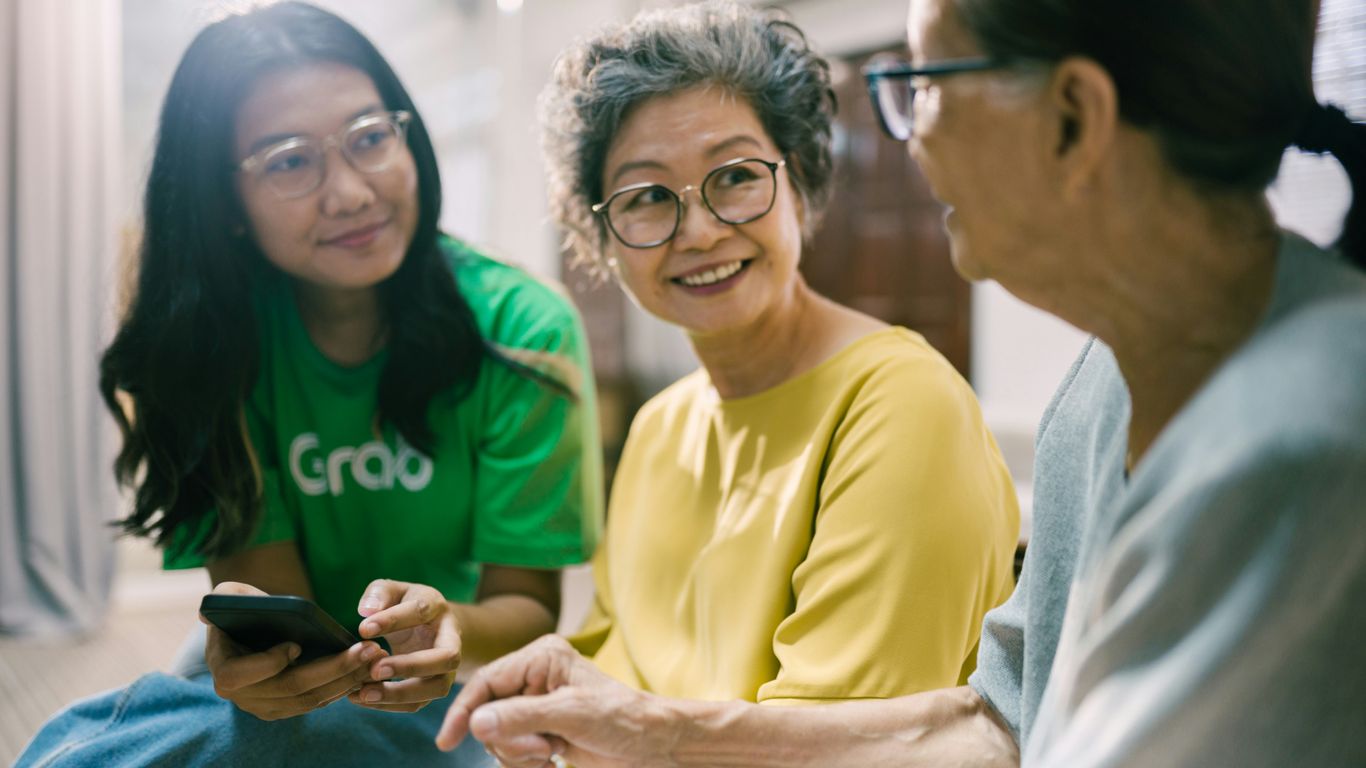 a group of women sitting on the floor looking at a cell phone