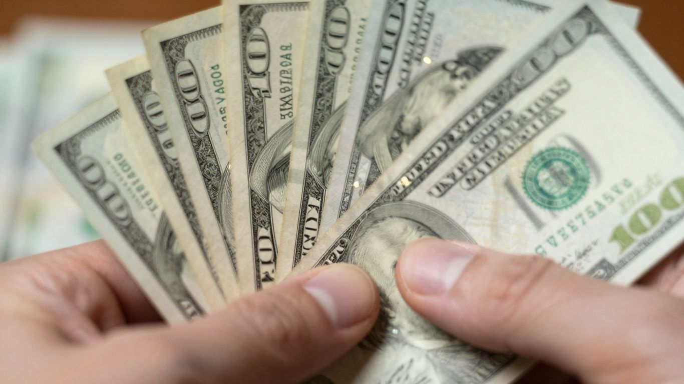 U.S. Treasury notes held in hand.