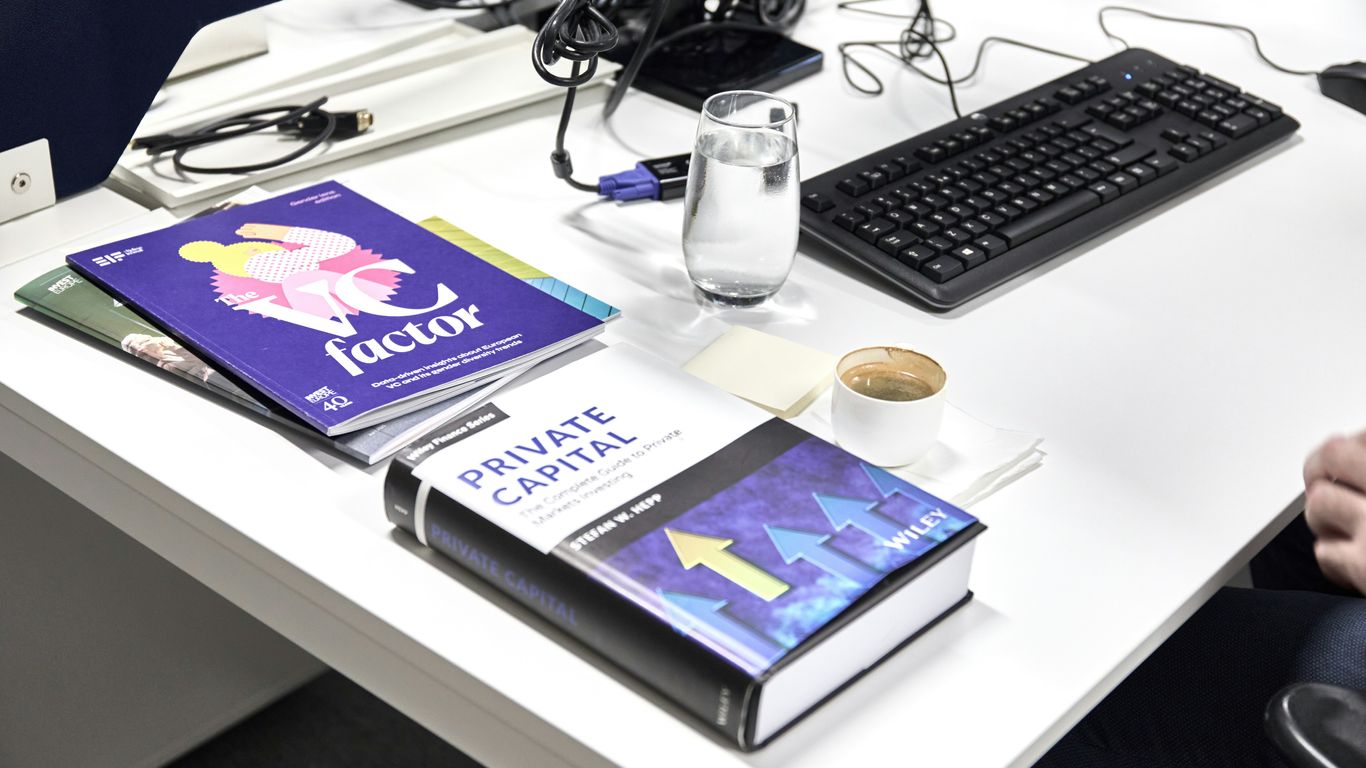 Desk with books, keyboard, and coffee cup of coffee.