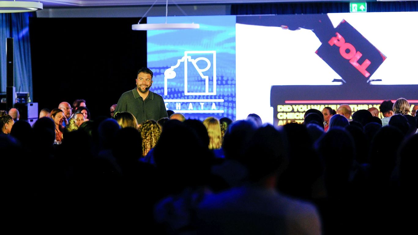 Man speaking on stage with audience watching