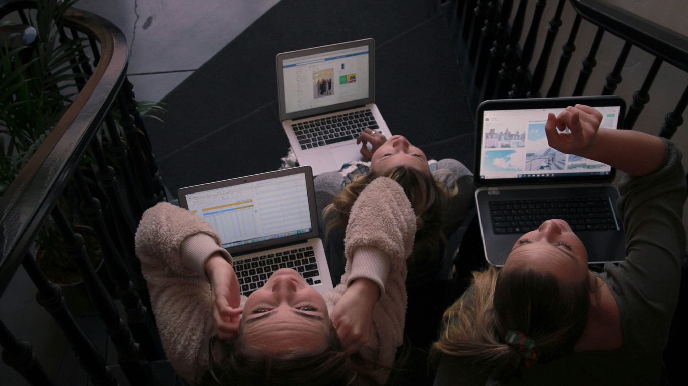 three person using laptops while sitting on ladder