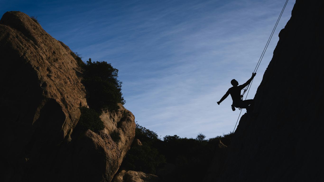 Silhouette of a climber scaling a rock face at dusk.