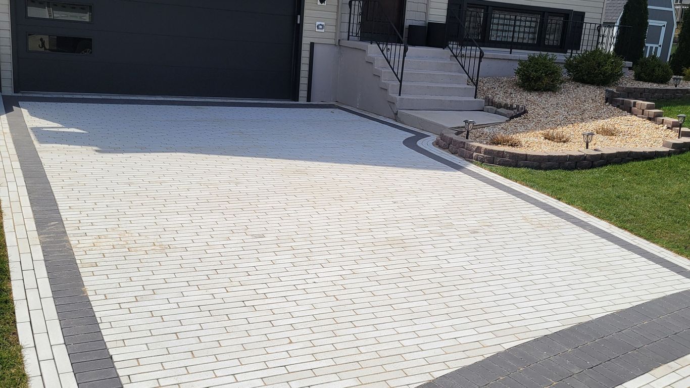 A newly paved driveway with a decorative border in front of a house.