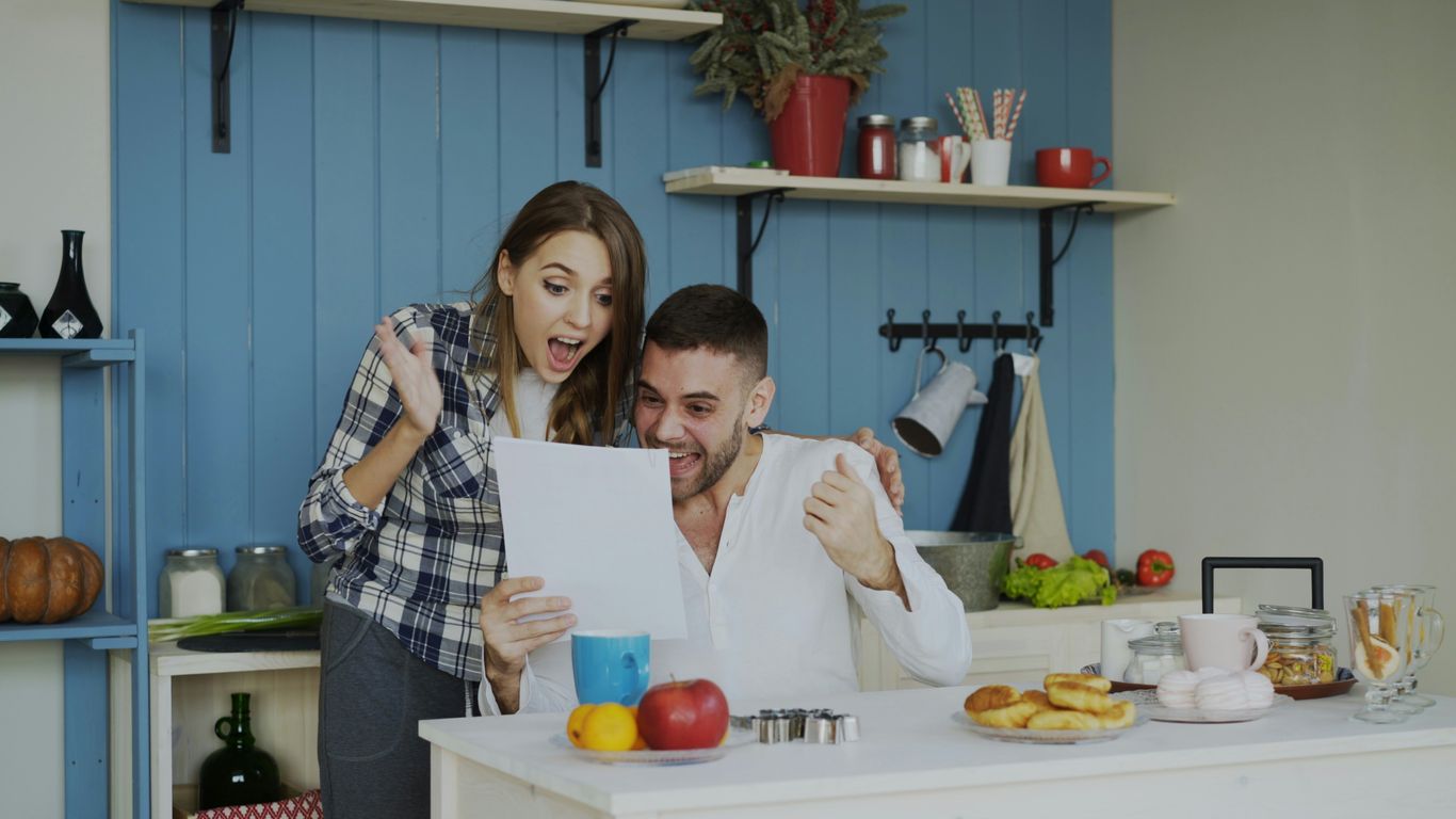 Couple celebrating good news while looking at paper.