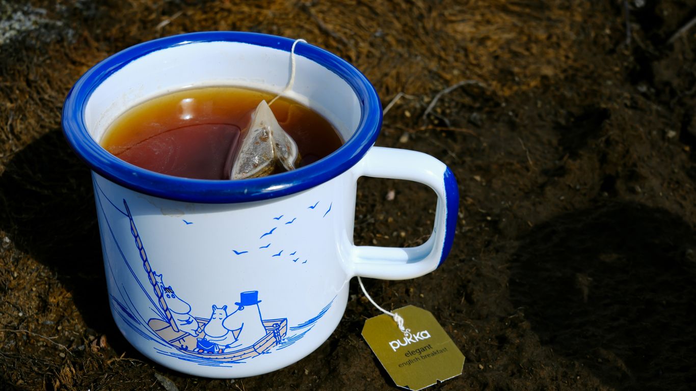 A cup of tea sitting on top of a dirt ground