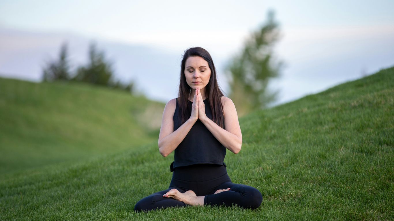 Person practicing yoga beside a quiet outdoor setting
