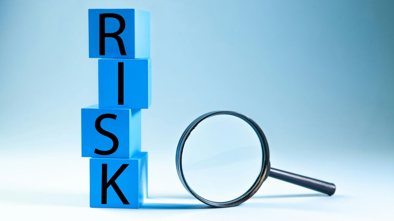 Blue blocks spelling risk next to a magnifying glass.