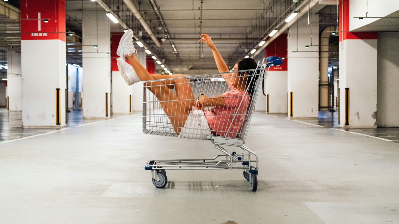 woman sitting in shopping cart at parking lot
