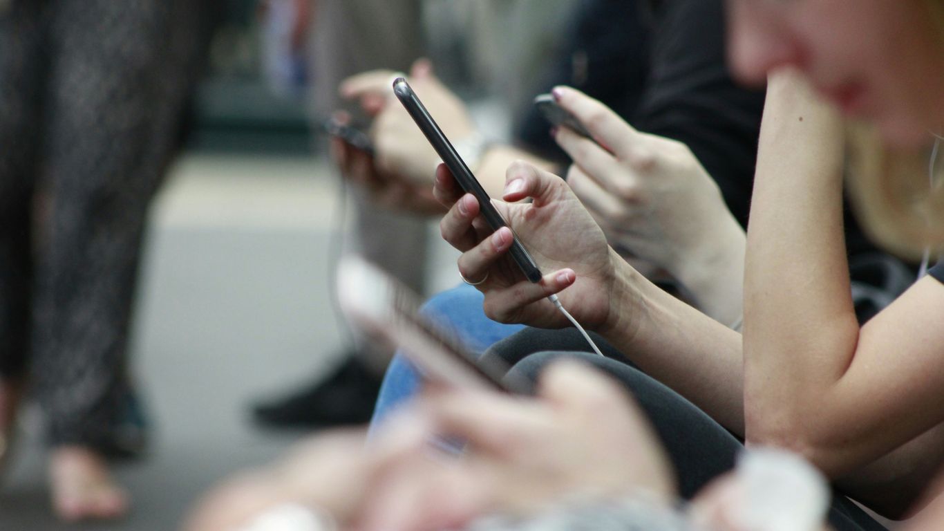 A diverse group of modern consumers happily interacting with their mobile phones
