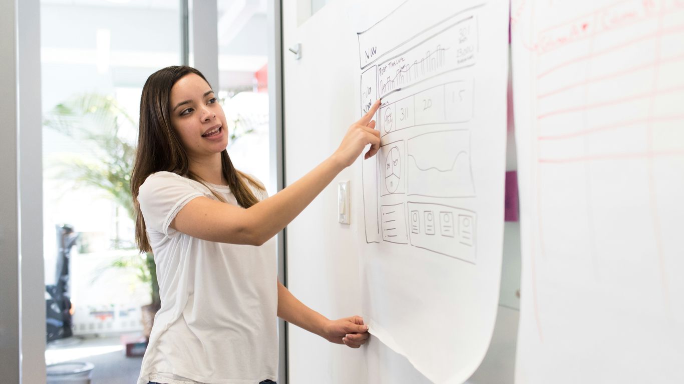 woman standing pointing paper on board