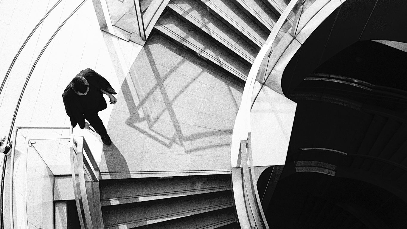 A man walks down modern spiral stairs.