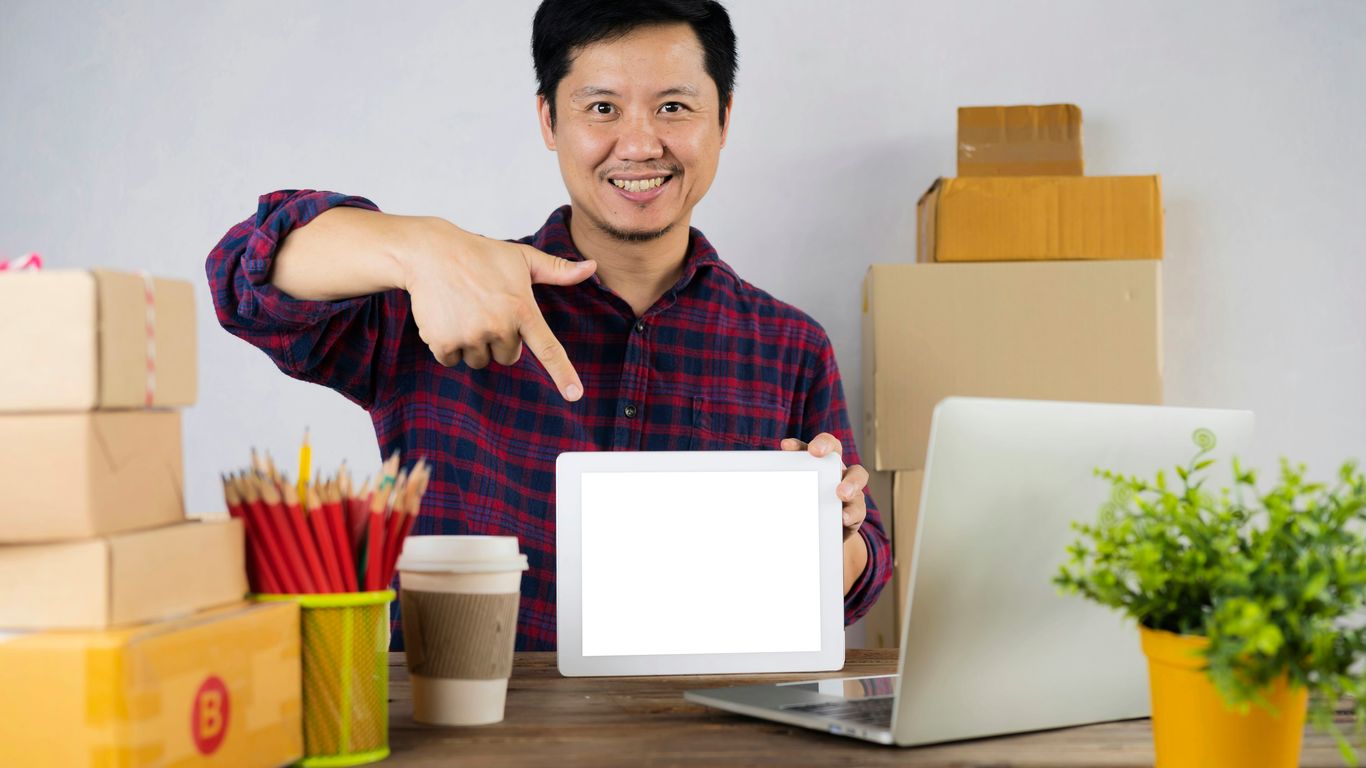 a man pointing at a laptop screen on a desk