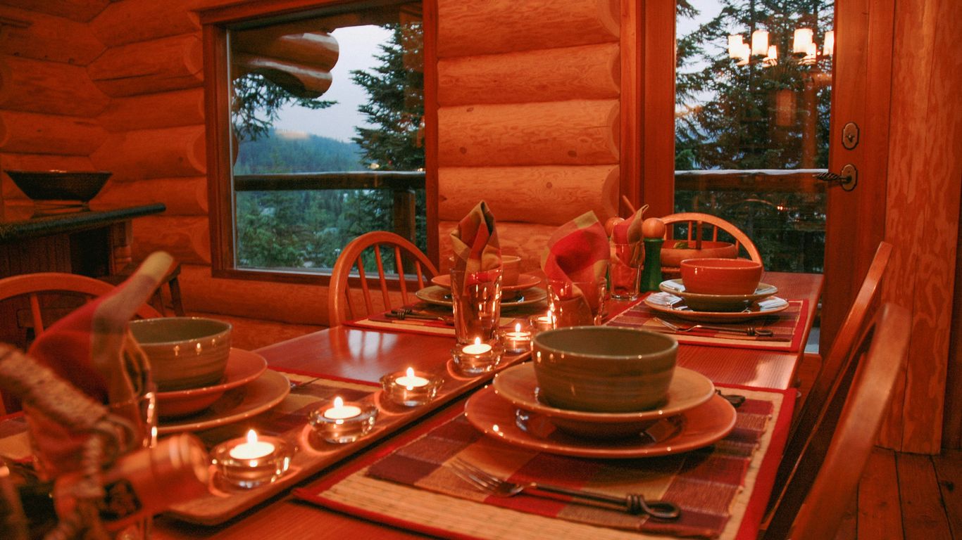 a dining room table set with place settings and candles