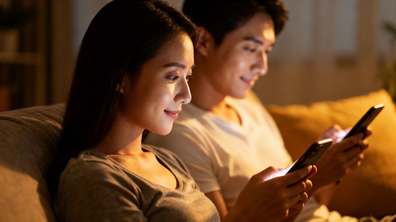 Couple on couch distracted by phones