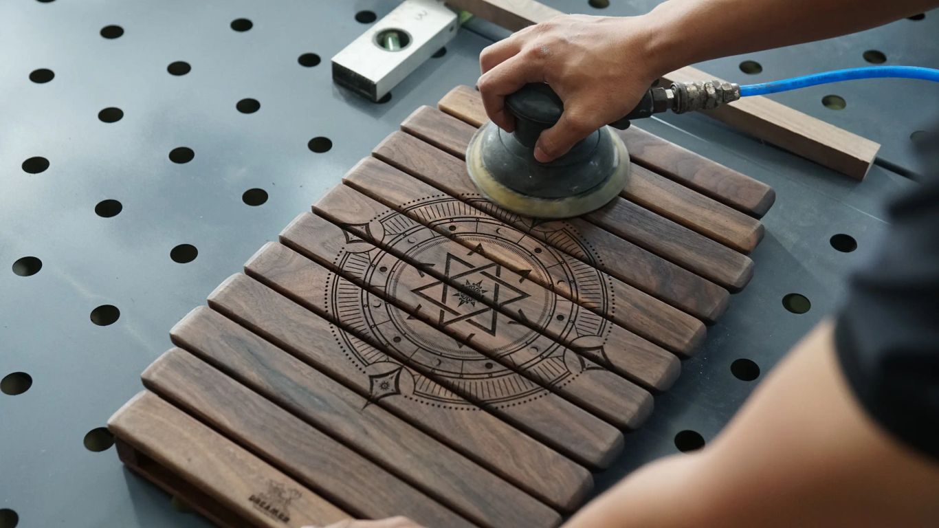 A person sands a wooden object with a circular design.