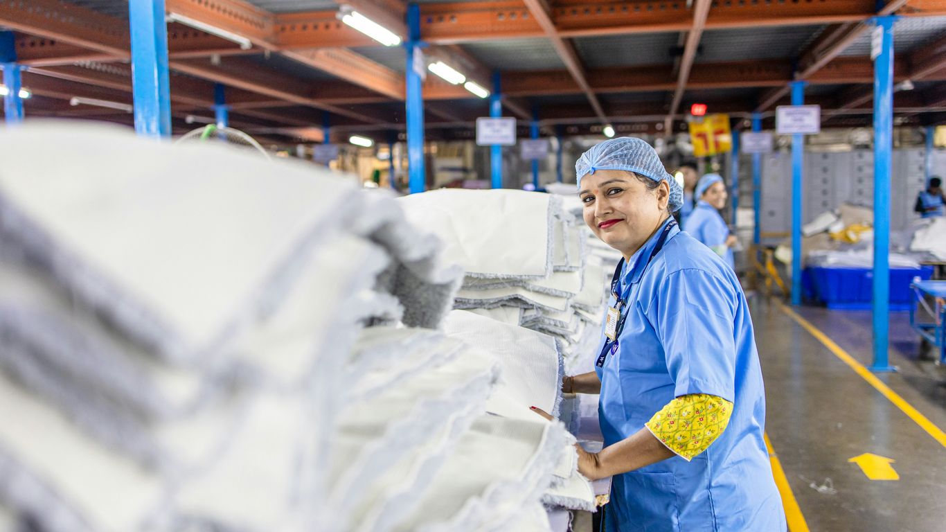 A textile worker smiles in a manufacturing facility.