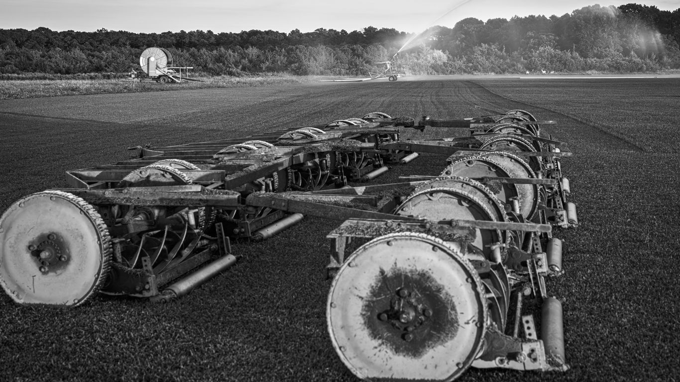 Agricultural machinery in a field with sprinklers.