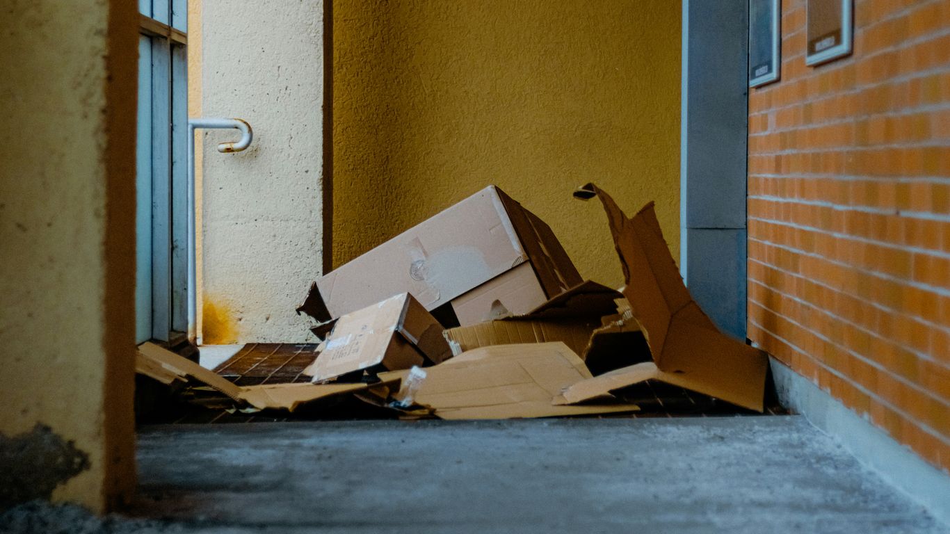 Cardboard boxes piled up outside a building entrance.