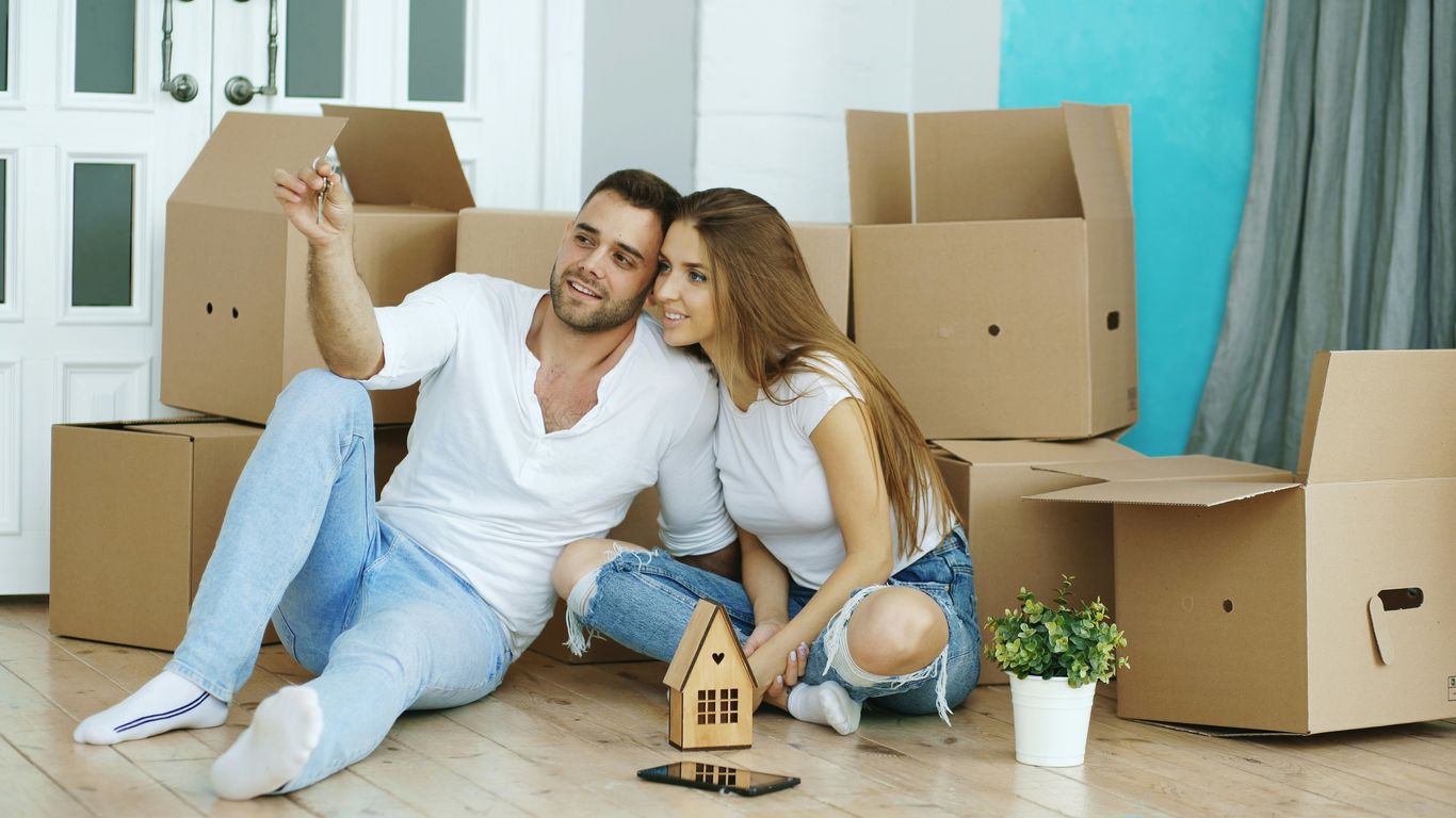 Couple sitting on floor surrounded by moving boxes