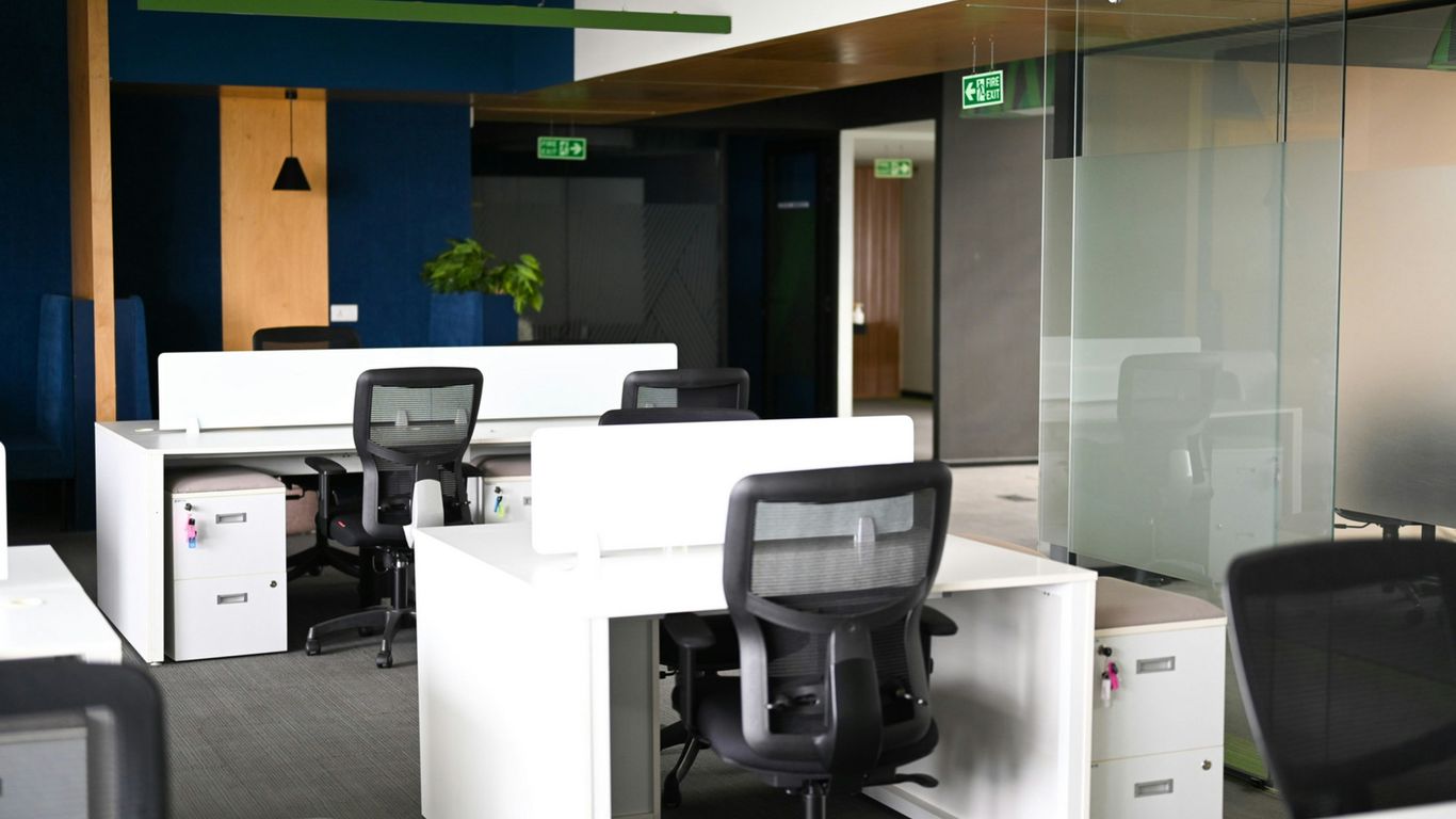 Modern office interior with white desks and black chairs.