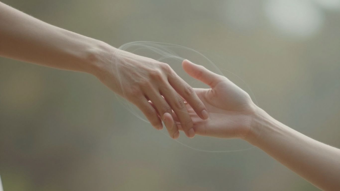 Two hands touching with ethereal light.