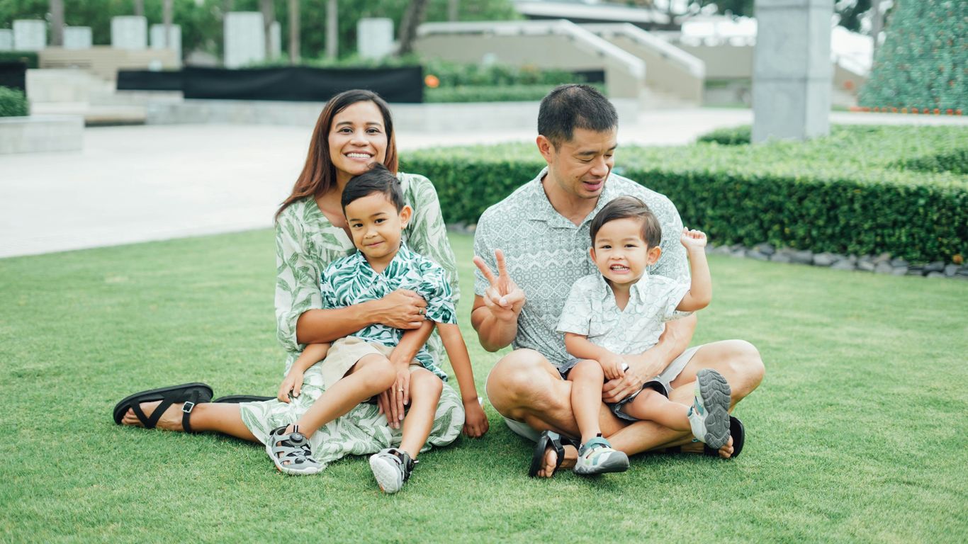 A happy family of four sitting on grass