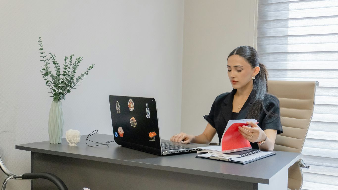 Woman working on a laptop at a desk.