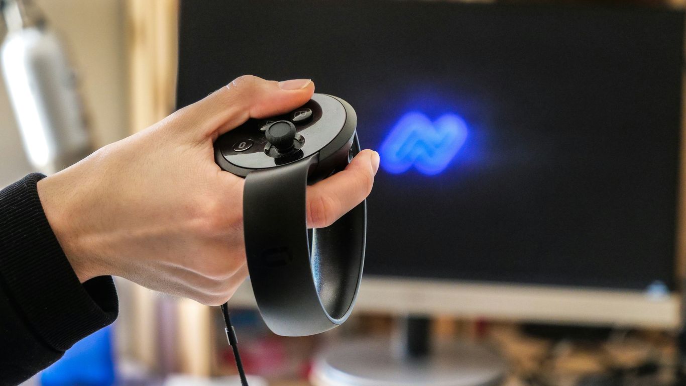 Hand holding vr controller with screen in background